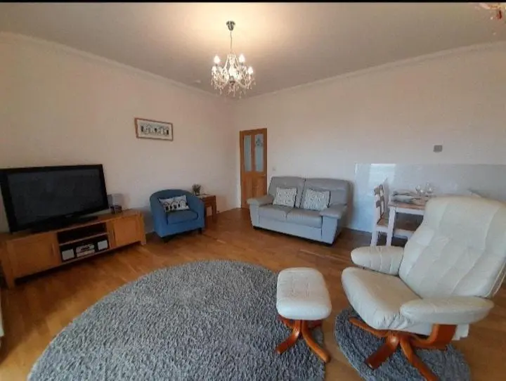 a living room with white furniture and a flat screen tv at Seabreeze in Whitehills