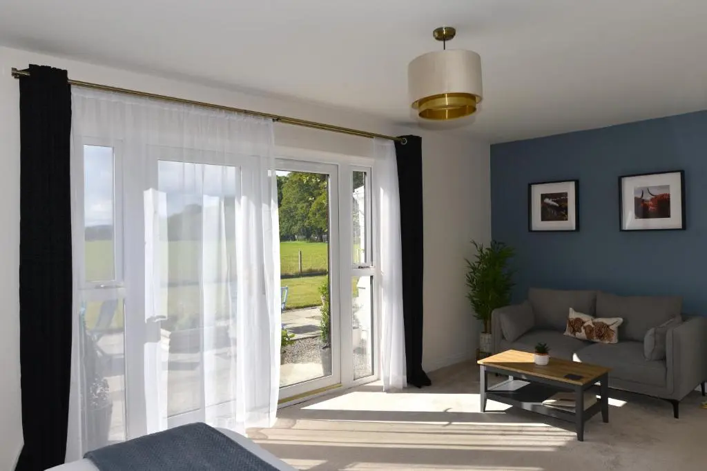 a living room with a couch and a large window at Coille Burn in Urray