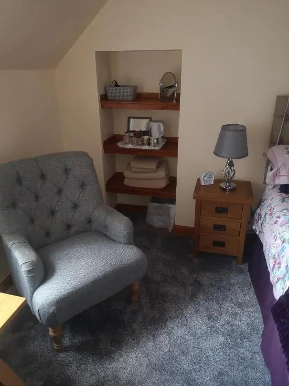 a bedroom with a chair and a bed and a lamp at Gladstone Cottage in Inverness