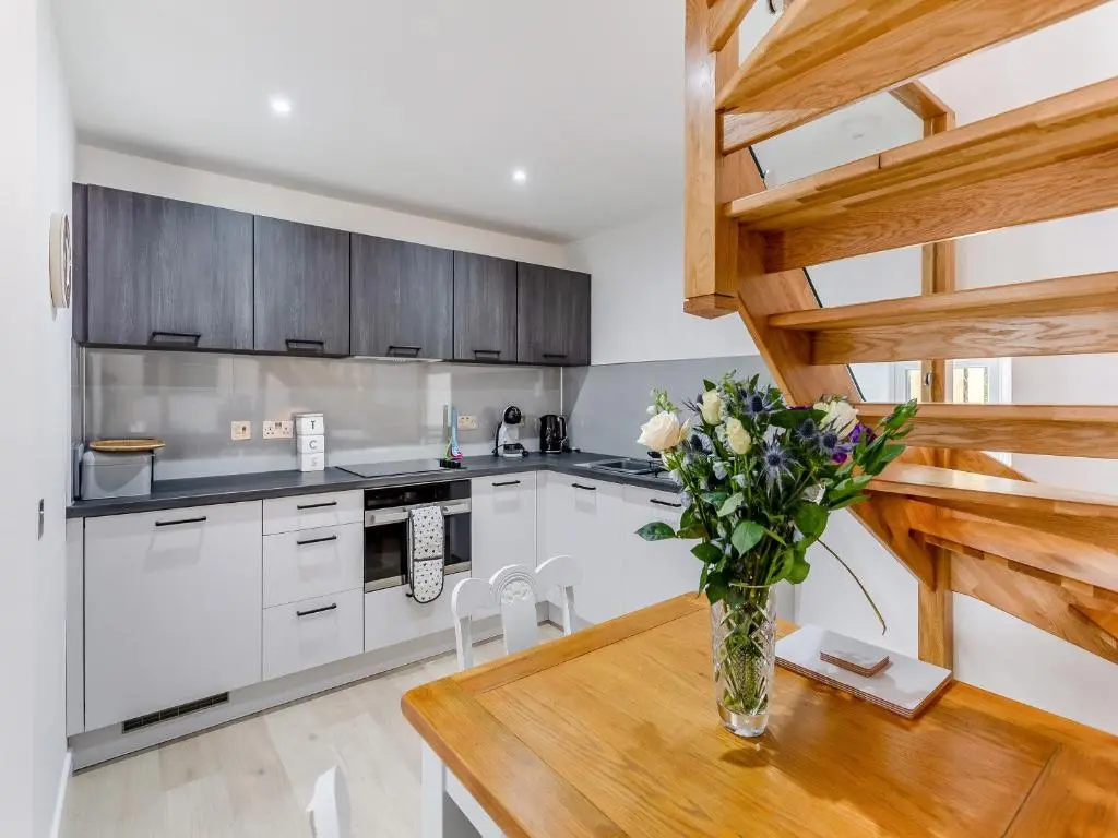 a kitchen with a wooden table and a vase of flowers at Ferry Cottage in Eskadale