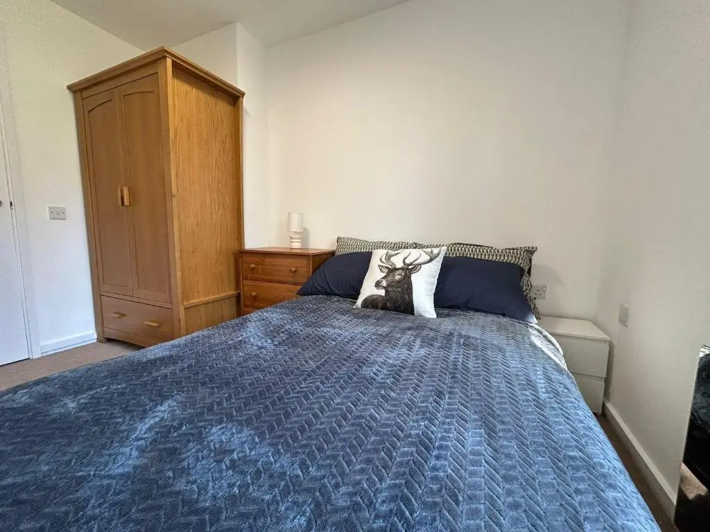 a bedroom with a bed with a blue comforter at Two bedroom cottage in Lumsden - Contractors in Huntly