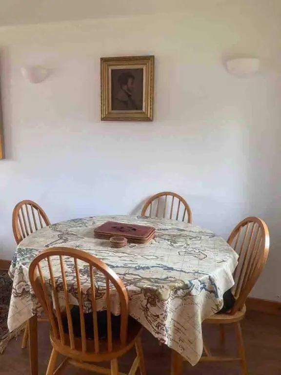 a table with four chairs and a picture on the wall at East Cottage, Brodie in Dyke