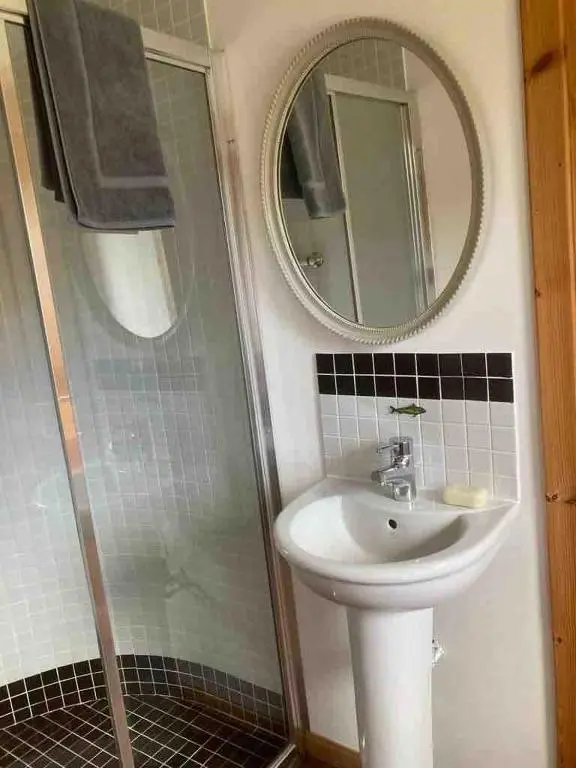 a bathroom with a sink and a shower with a mirror at East Cottage, Brodie in Dyke