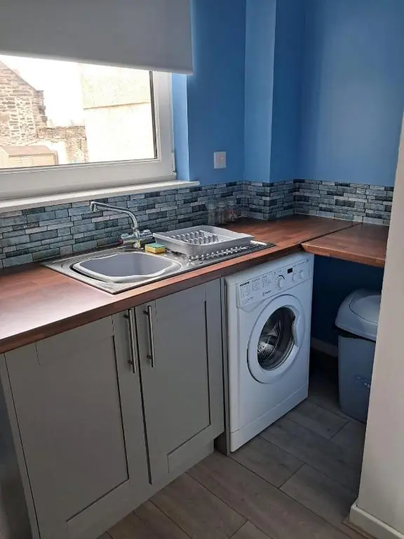 a kitchen with a sink and a washing machine at Granny's Hoose in Wick