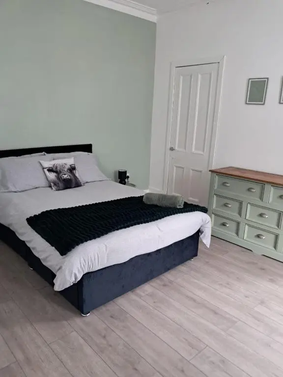 a bedroom with a large bed and a dresser at Granny's Hoose in Wick