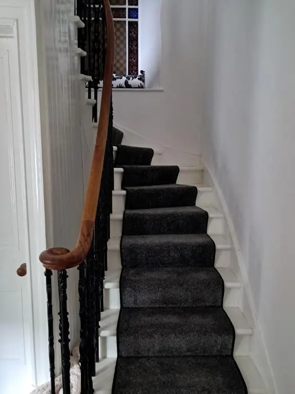 a staircase in a house with a wooden hand rail at Granny's Hoose in Wick