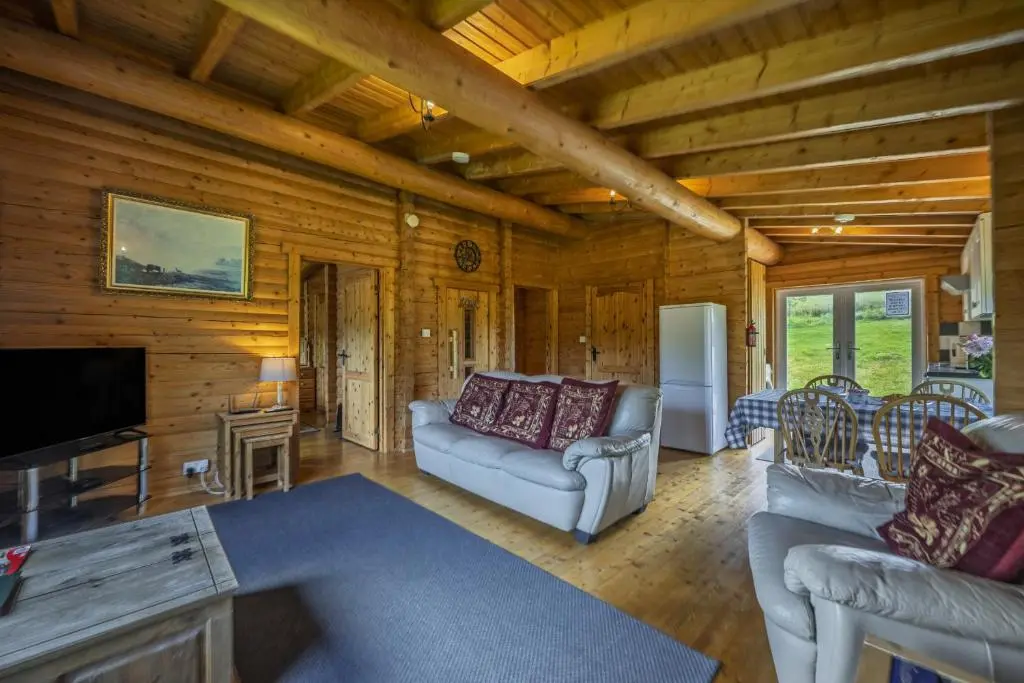 a living room with a couch and a tv at Finest Retreats - Cragdhu Log Cabin in Glenshee