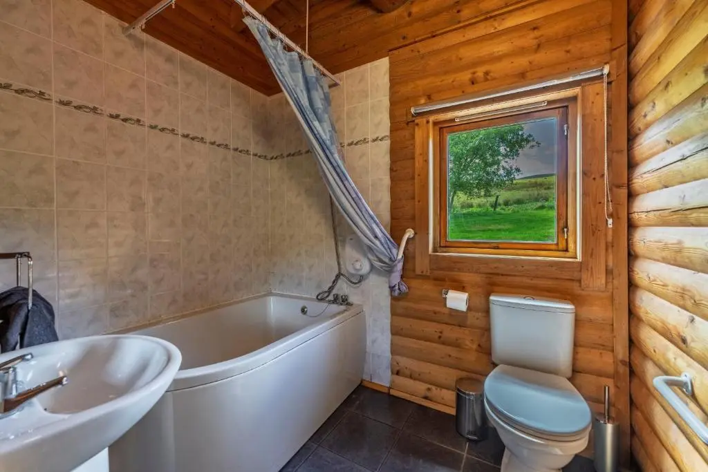 a bathroom with a tub and a toilet and a sink at Finest Retreats - Cragdhu Log Cabin in Glenshee