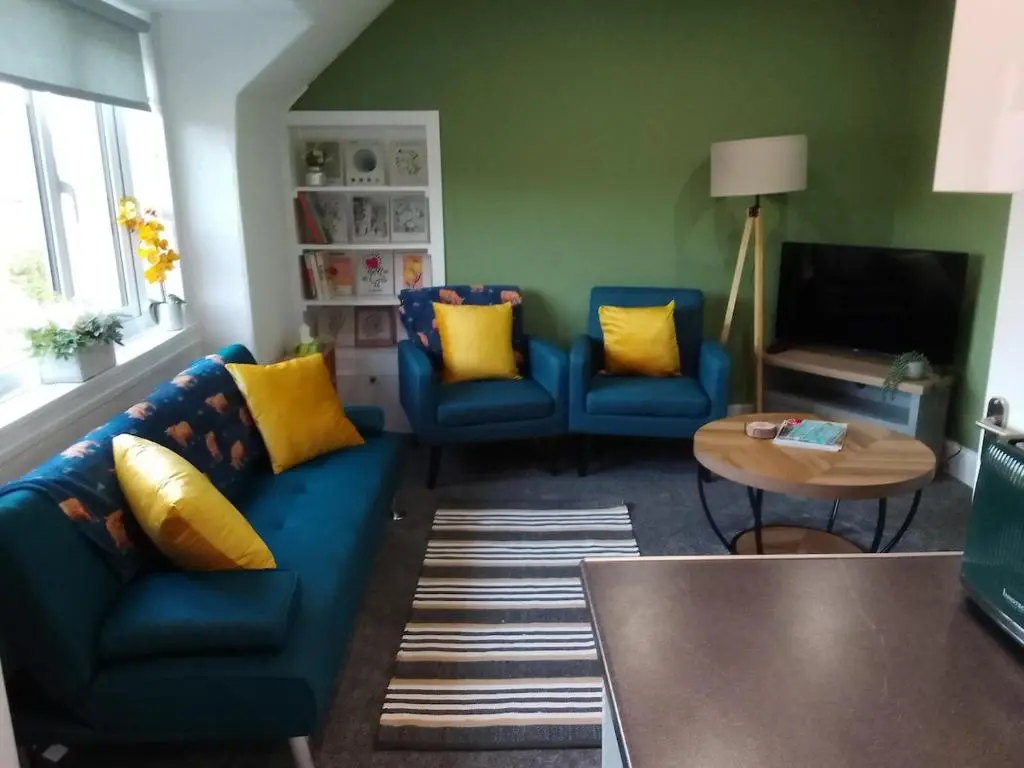 a living room with a blue couch and yellow pillows at Cosy Crown 1 bedroom flat for up to 4 guests in Inverness