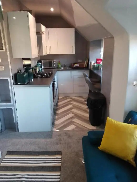 a kitchen with white cabinets and a blue couch at Cosy Crown 1 bedroom flat for up to 4 guests in Inverness