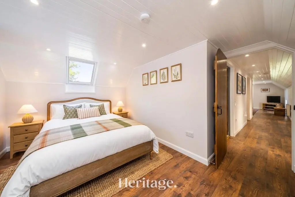 a bedroom with a large bed and a hallway at The Byre, Countryside Home in Tough