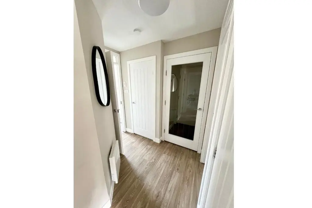 a hallway with white walls and a mirror at Flat by the Firth - Stay in the heart of Nairn in Nairn