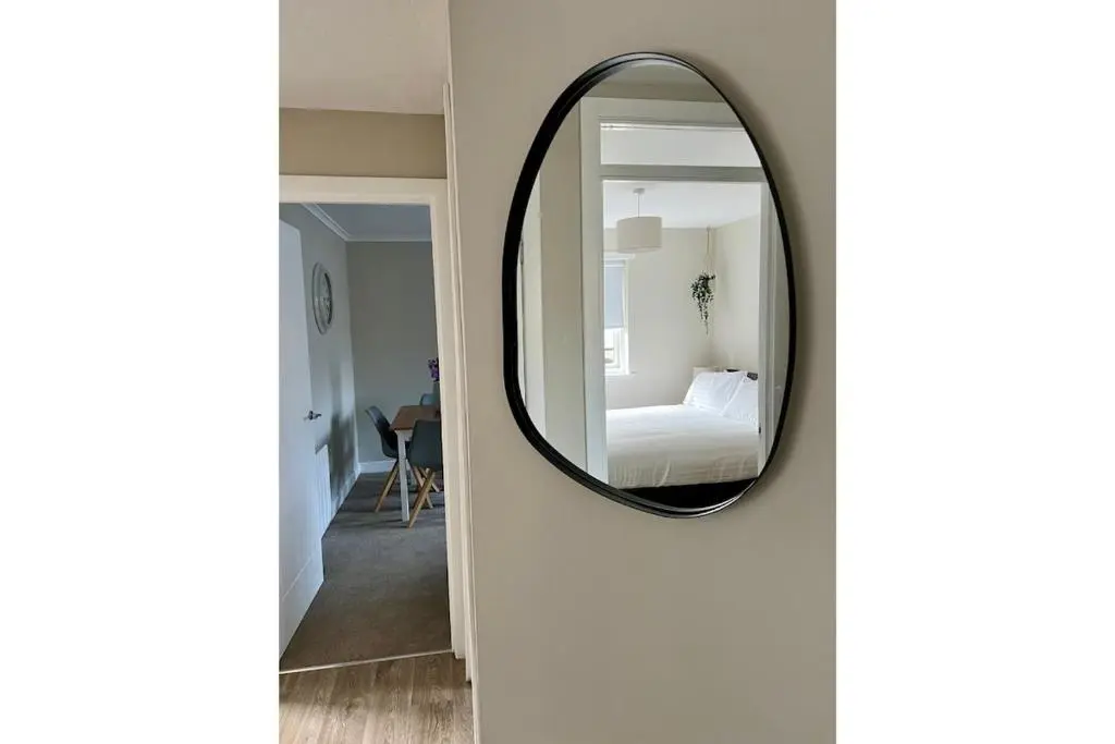 a mirror on a wall next to a bedroom at Flat by the Firth - Stay in the heart of Nairn in Nairn
