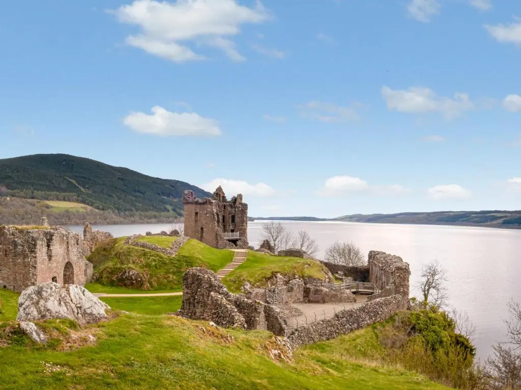 an old castle on a hill next to a body of water at Holiday Home Shepherds Hut by Interhome in Balnain