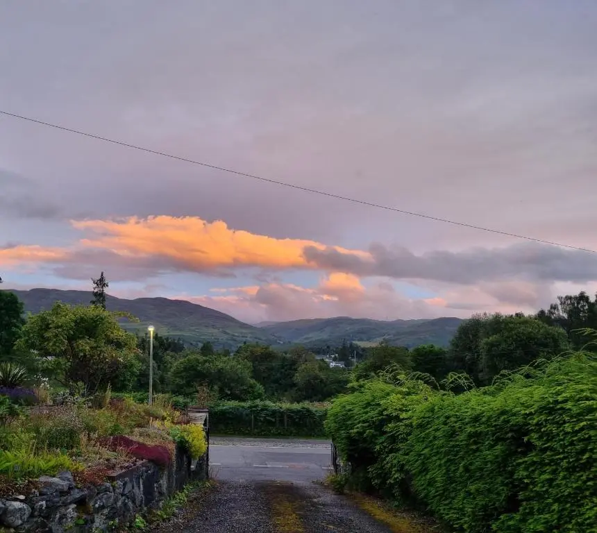 an empty road with a sunset in the sky at Bailem Lodge at Loch Ness ADULTS ONLY in Fort Augustus