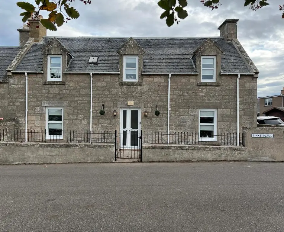 an old brick building with a white door at 1 Links Place in Nairn