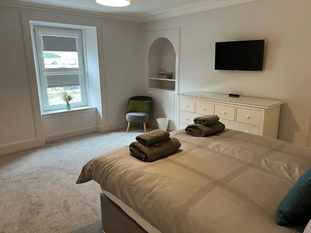 a bedroom with a bed with two towels on it at 1 Links Place in Nairn