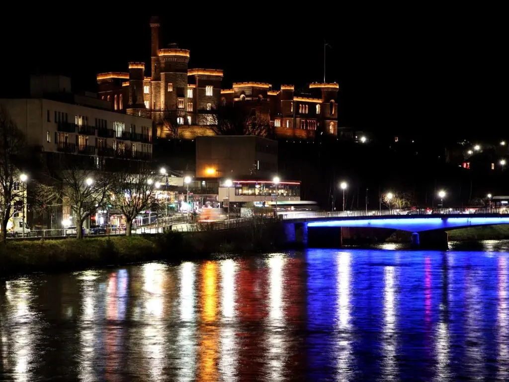 a bridge over a river with a city at night at View Apartment in Inverness