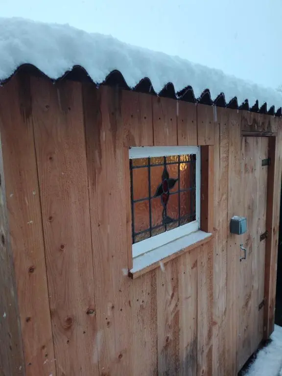 a bird sitting in a window of a wooden house at 'Wee Smiddy' Shepherd's Hut - Sauna - Yoga - Wild Swim in Skye of Curr