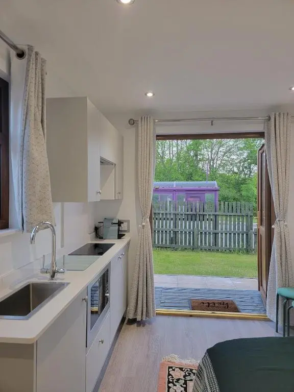 a kitchen with a sink and a door to a yard at 'Wee Smiddy' Shepherd's Hut - Sauna - Yoga - Wild Swim in Skye of Curr