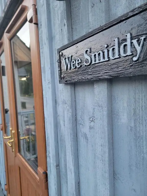 a sign on the side of a building with a door at 'Wee Smiddy' Shepherd's Hut - Sauna - Yoga - Wild Swim in Skye of Curr