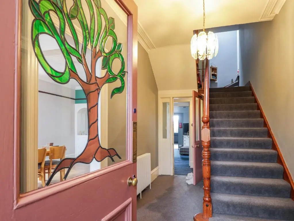 a hallway with a staircase with a stained glass tree on the door at Crannoch Self Catering in Buckie
