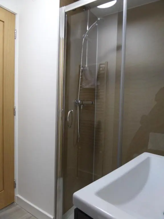 a glass shower in a bathroom with a sink at Church Street Apartments in Inverness
