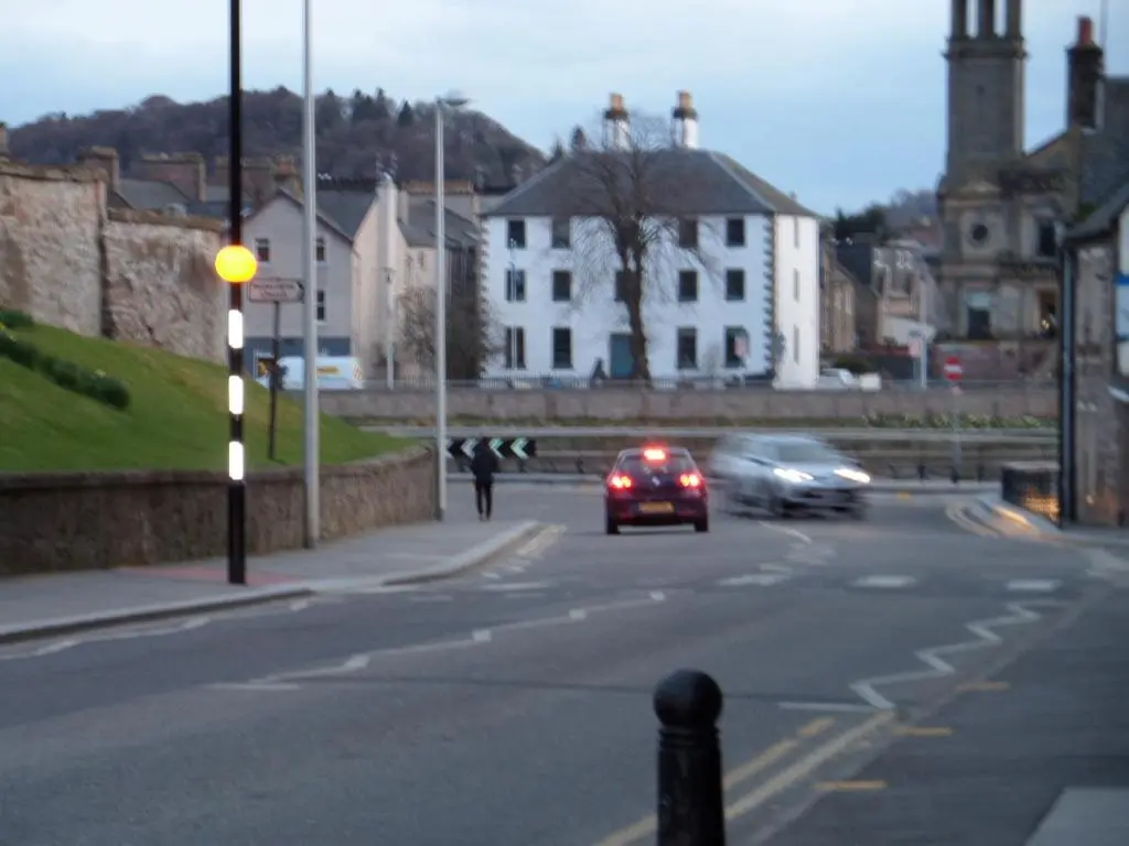 a car driving down a city street with cars at Church Street Apartments in Inverness