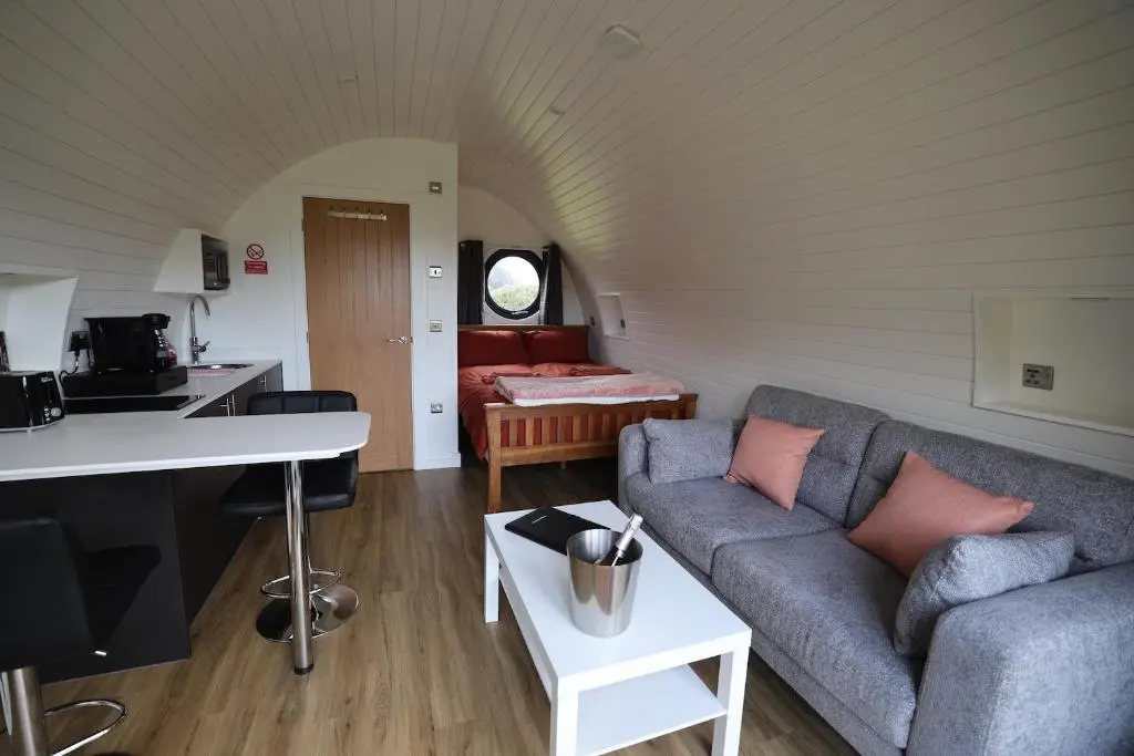 a living room with a couch and a table at Lochend Pods - Deas Pod in Inverlael
