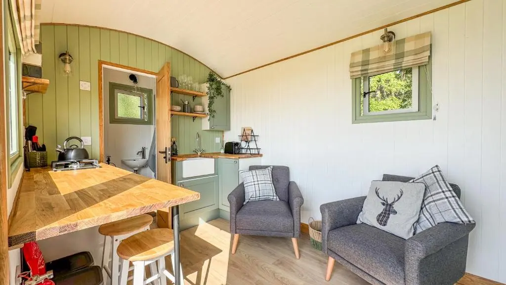 a small kitchen with a table and two chairs at Cnocvann Croft Shepherd Huts in Kilmorack