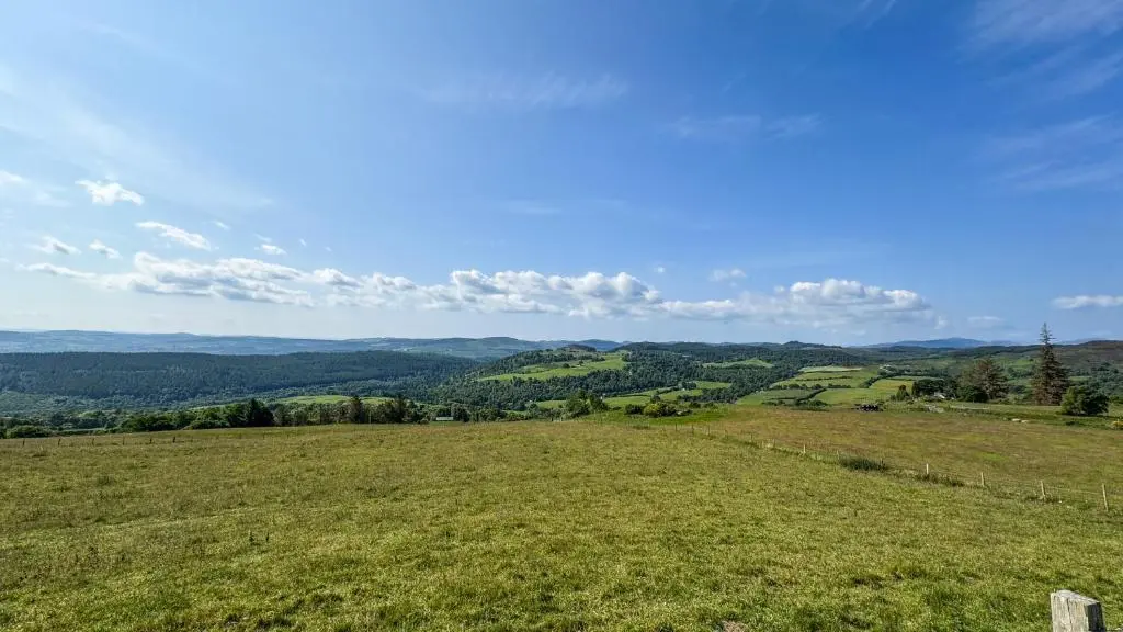 a field of grass with a view of the hills at Cnocvann Croft Shepherd Huts in Kilmorack