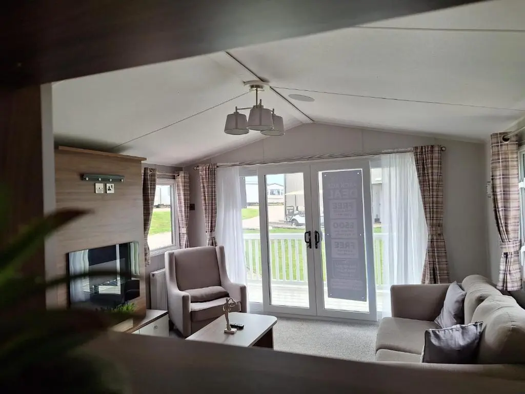a living room with a couch and chairs and a tv at Northern Lights in Lossiemouth