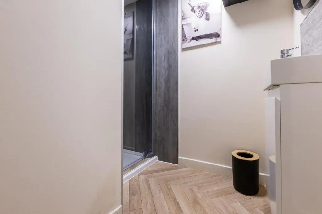 a kitchen with a refrigerator and a wooden floor at Alba Apartment in Inverness