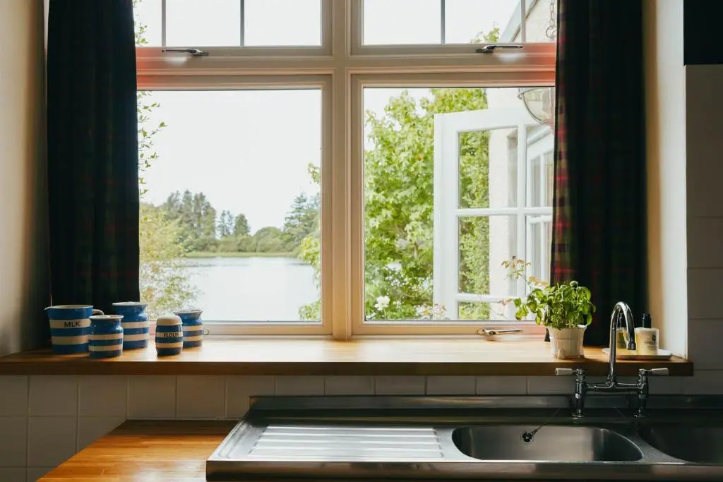 a kitchen window with a view of a lake at The Secret Loch in Lhanbryd