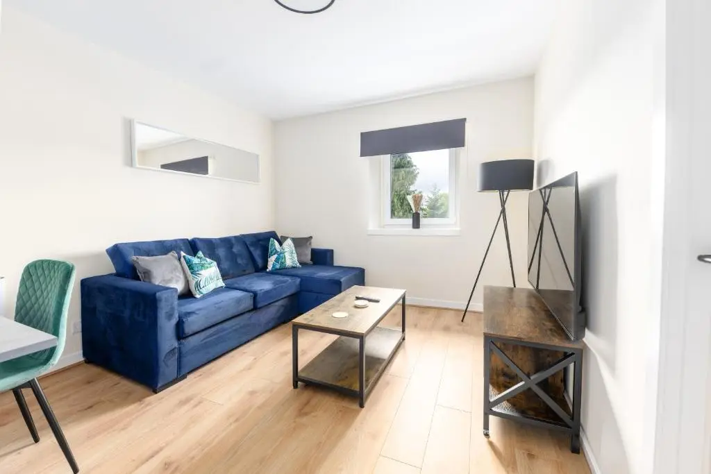 a living room with a blue couch and a table at 1 BDR Flat At Caledonia Luxe Stays Short Lets & Serviced Accommodation Inverness in Inverness