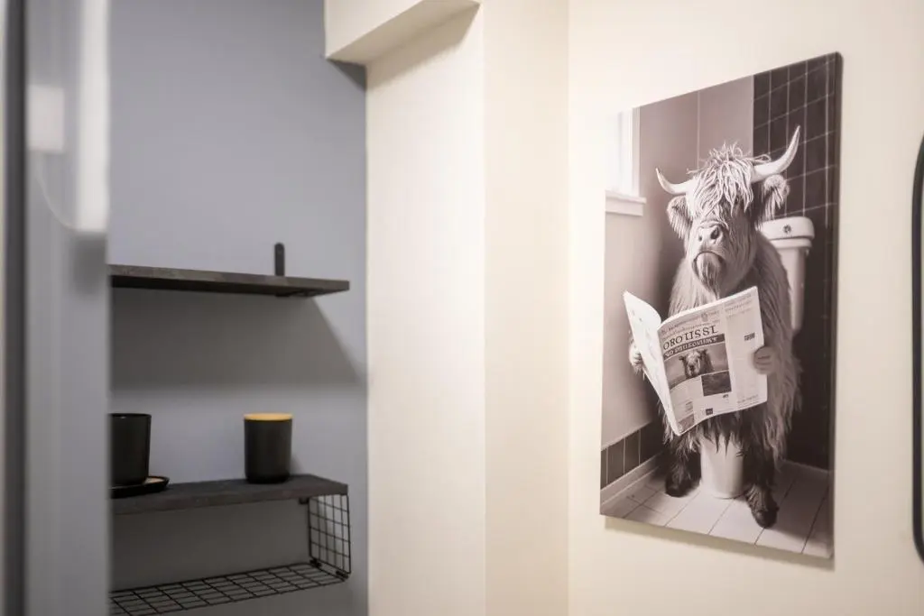 a picture of a cow in a bathroom with a newspaper at 1 BDR Flat At Caledonia Luxe Stays Short Lets & Serviced Accommodation Inverness in Inverness