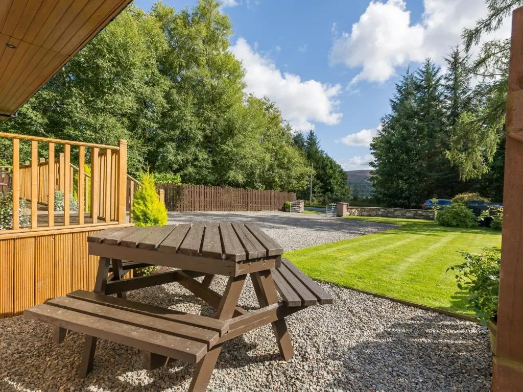 a wooden picnic table sitting next to a yard at Broombank Cottage in Inverness