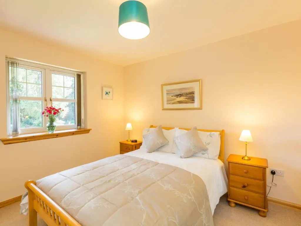 a bedroom with a bed and two windows at Broombank Cottage in Inverness