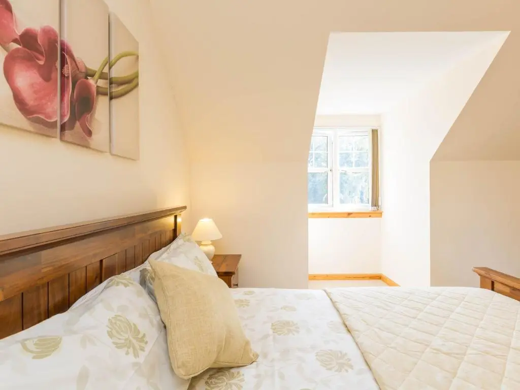 a bedroom with a bed and a window at Broombank Cottage in Inverness