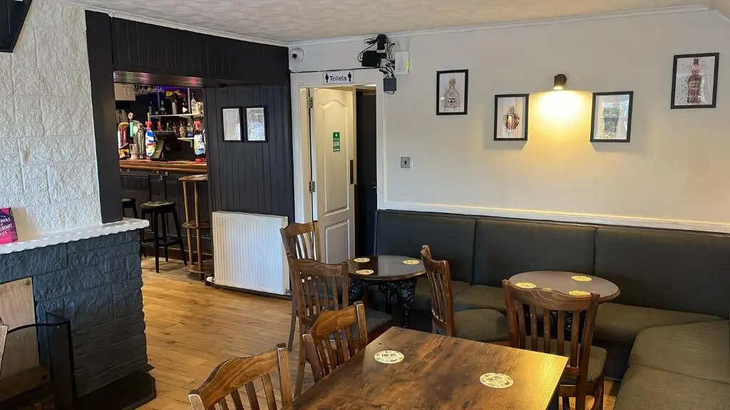 a restaurant with a table and chairs and a bar at Novar Arms Hotel in Evanton