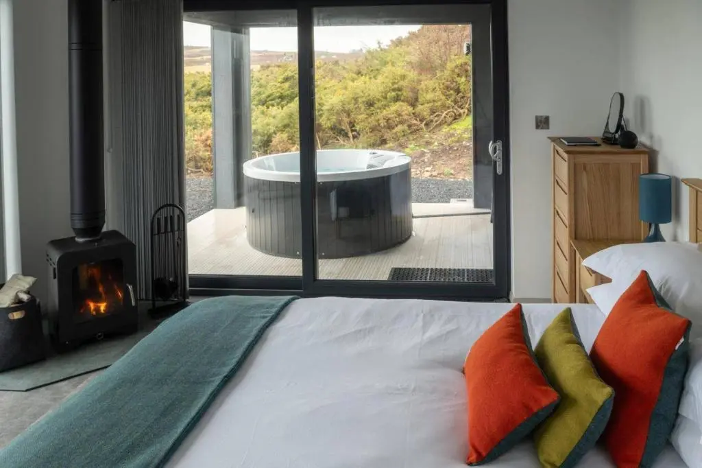 a bedroom with a tub with a bed and a fireplace at Migdale Heights - Luxury Cabins in The Highlands in Bonar Bridge
