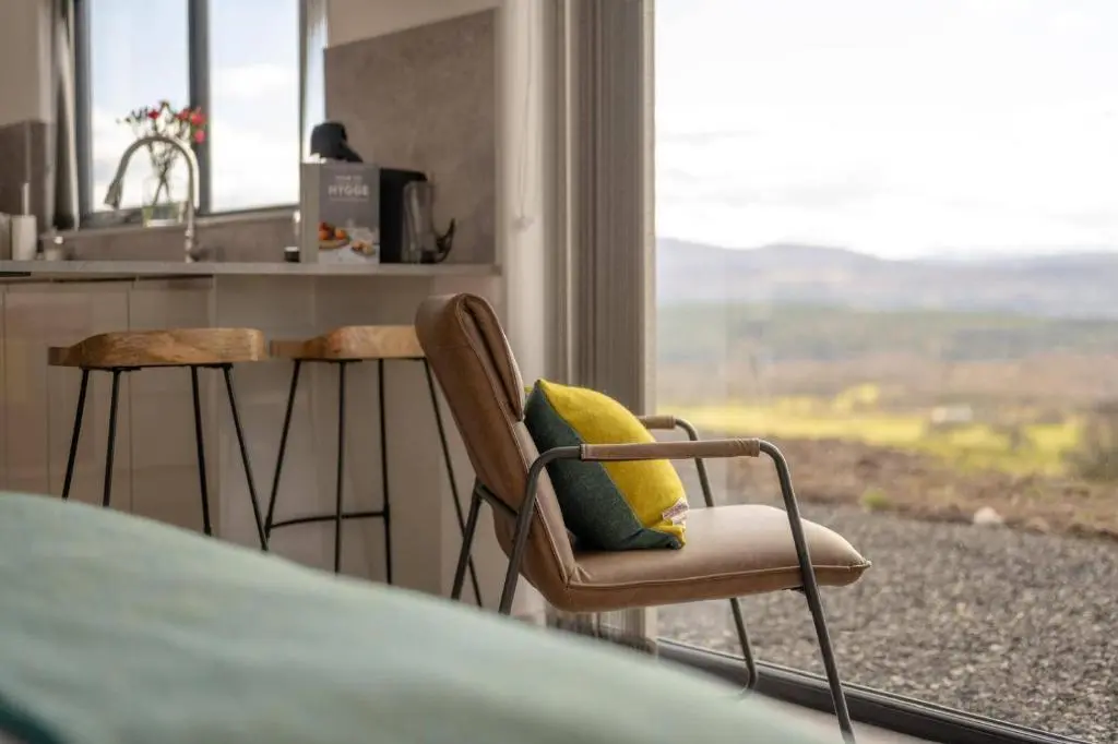 a kitchen with two chairs and a counter and a window at Migdale Heights - Luxury Cabins in The Highlands in Bonar Bridge