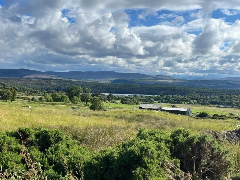 a view of a field with a barn in the distance at Migdale Heights - Luxury Cabins in The Highlands in Bonar Bridge