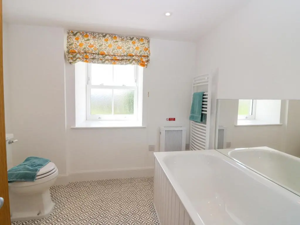 a bathroom with a toilet and a tub and a window at The Crannach in Blairgowrie