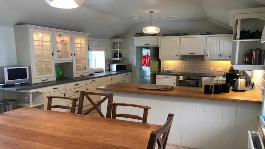 a kitchen with white cabinets and a wooden table at Dhivach Lodge in Drumnadrochit