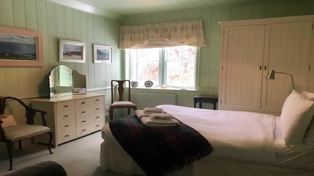 a bedroom with a bed and a chair and a mirror at Dhivach Lodge in Drumnadrochit