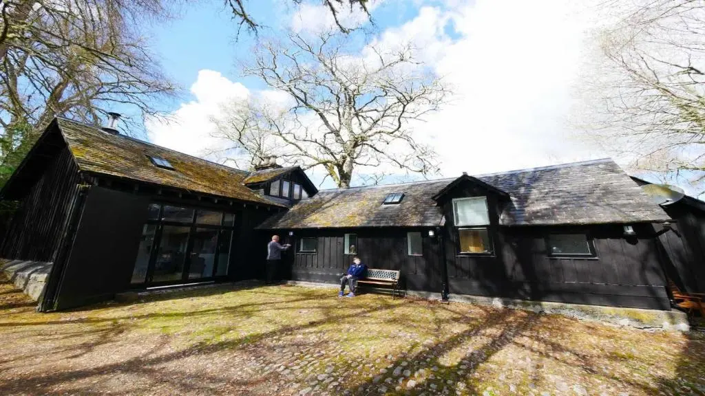 a man standing in front of a black house at Coach House in Drumnadrochit