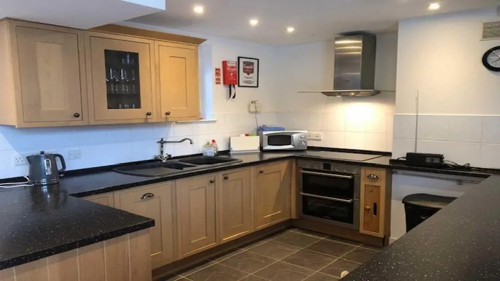 a kitchen with wooden cabinets and black counter tops at Coach House in Drumnadrochit