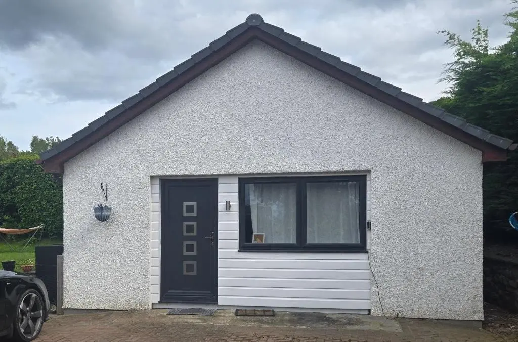 a small white house with a black door at Charlies Cottage in Inverness