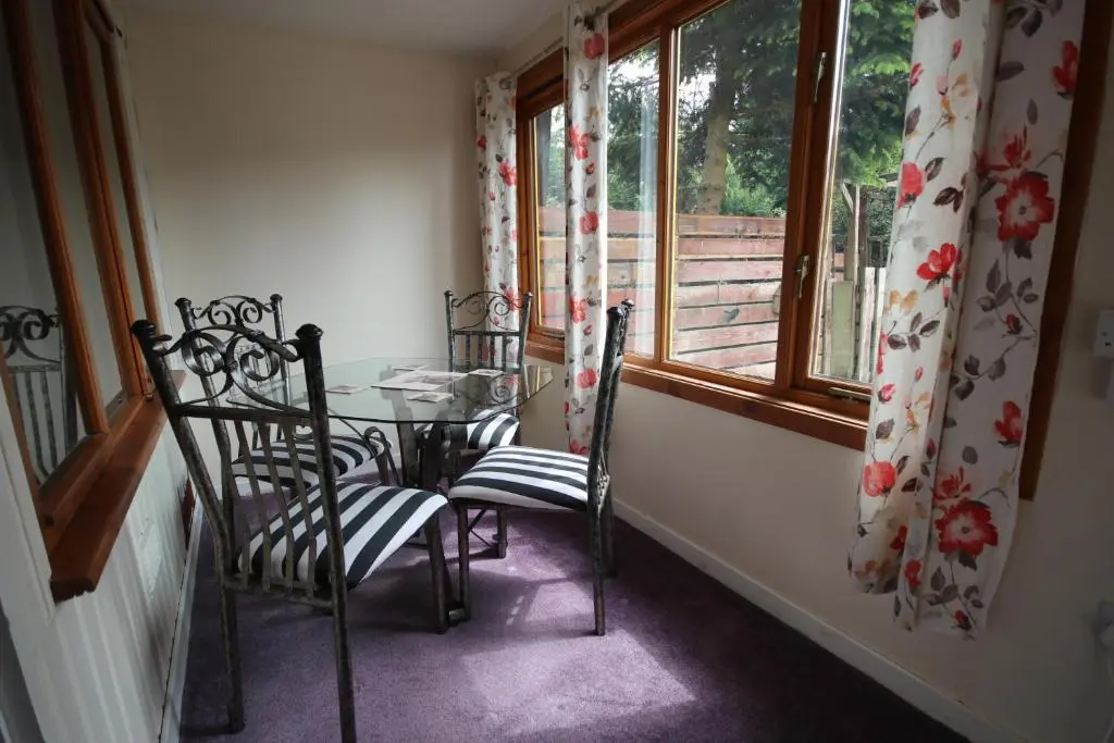 a dining room with a table and chairs and a window at Woodlands Rest in Garve